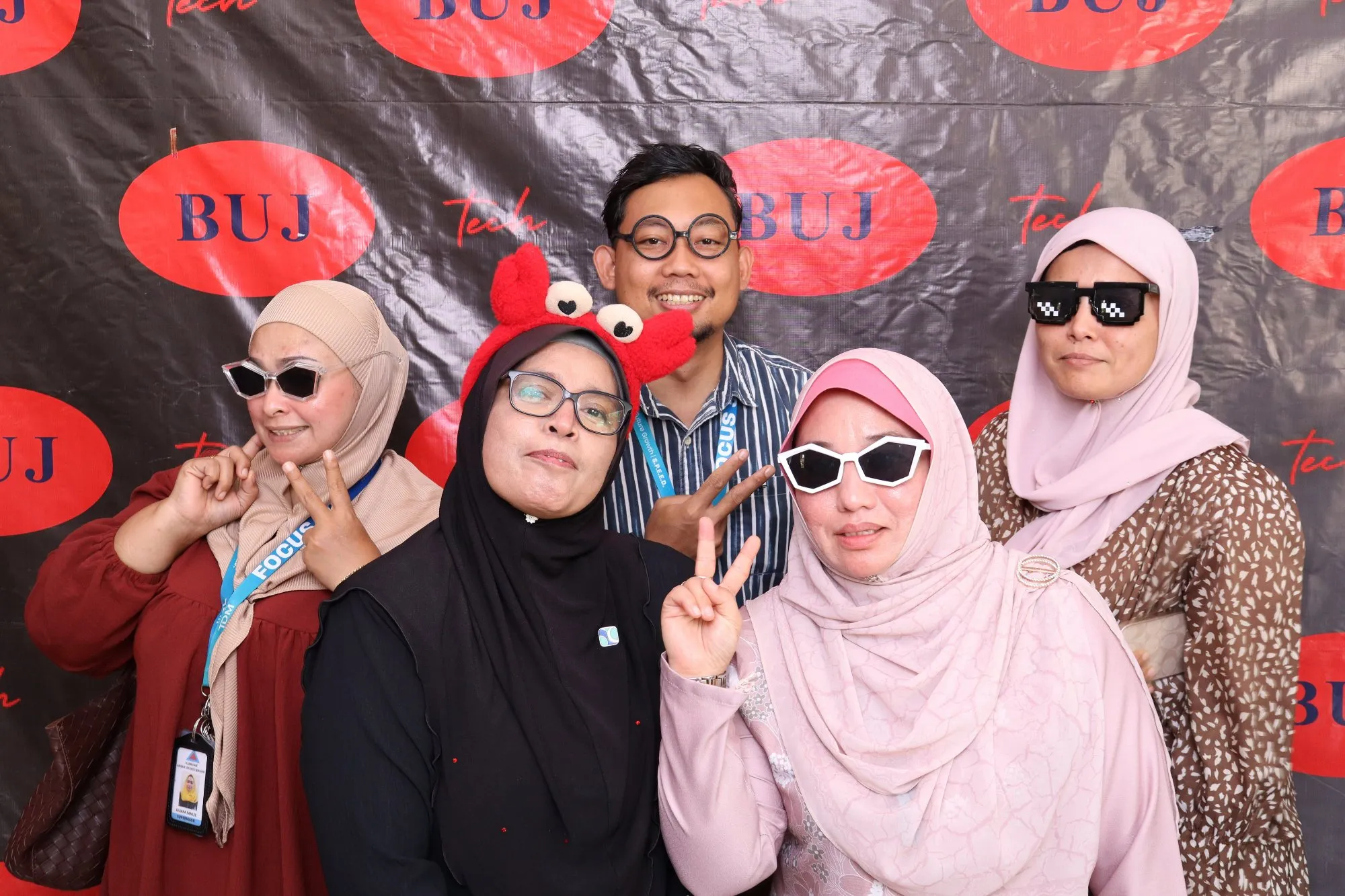 Aksi tetamu di depan backdrop photobooth pada rumah terbuka hari raya Sambutan Hari Raya bersama BUJ Technology di BCIC Lodge