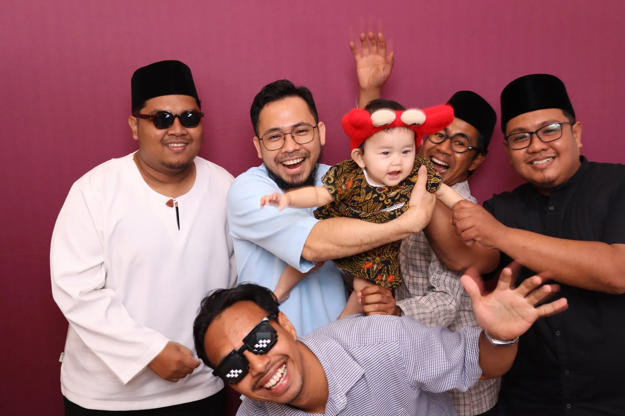 Aksi tetamu di depan backdrop photobooth pada rumah terbuka hari raya Riang Raya AIA di Timorra Venue