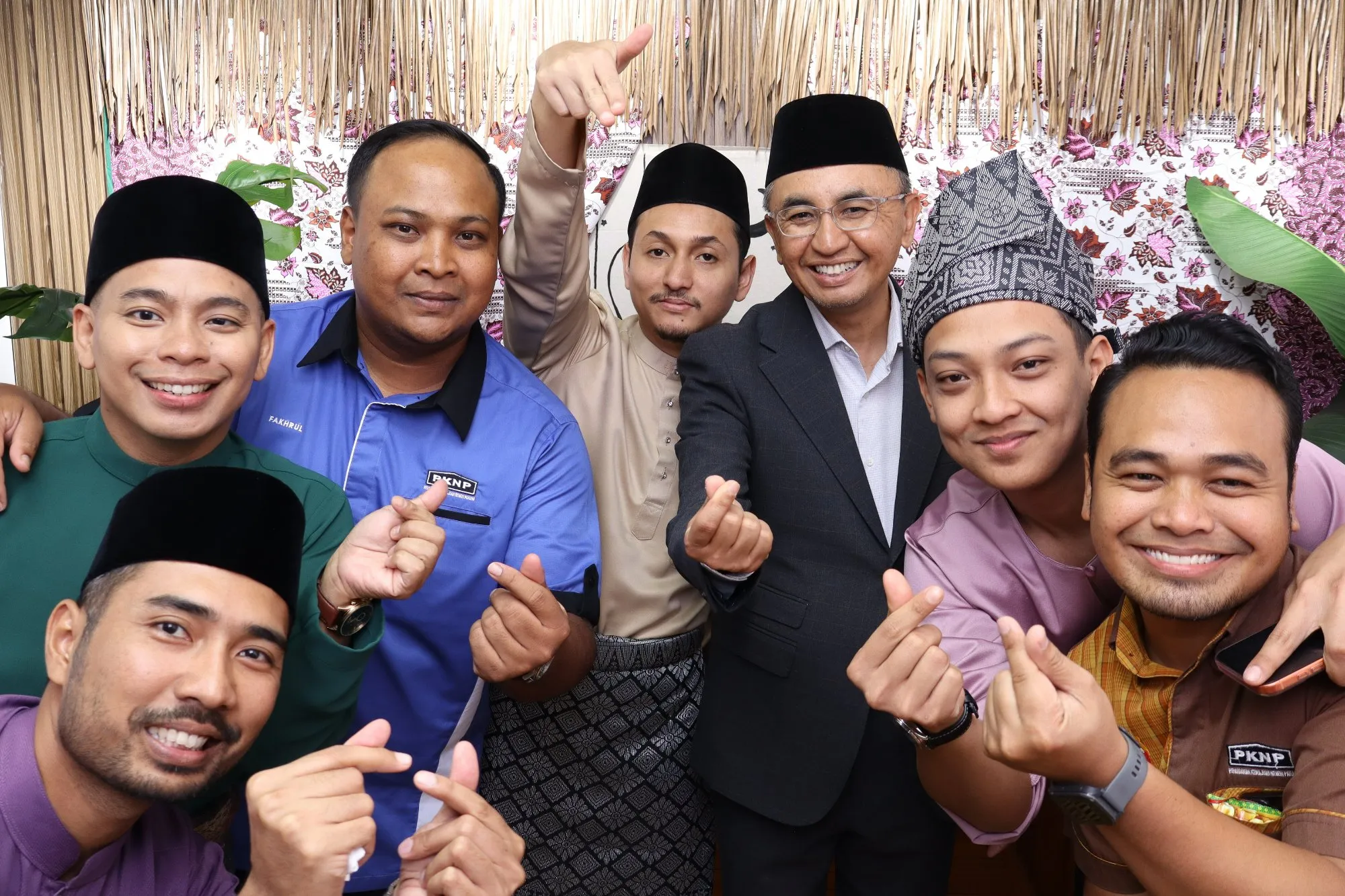 Aksi tetamu di depan backdrop photobooth pada rumah terbuka hari raya Pasar Ria Raya PKNK di PKNP Kompleks Teruntum